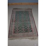 Afghanistan style wool rug with a green white and red ground, decorated with diamond lozenge guls