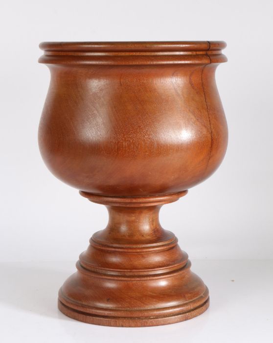 A 19th/20th century turned wooden mortar, of large proportions, the bulbous bowl raised on a stepped