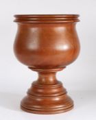 A 19th/20th century turned wooden mortar, of large proportions, the bulbous bowl raised on a stepped