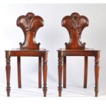 A pair of Regency mahogany hall chairs, carved scrollwork backs, shaped and dished solid seats,