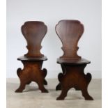 Pair of George III mahogany hall chairs, circa 1800, each of sgabello form, the solid back above a