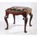 A George III mahogany stool, the drop in seat with foliate decoration above an undulating frieze and