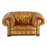 A leather upholstered deep armchair, the button back and scroll arms above the button seat raised on