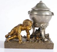 A 19th century French gilt bronze inkstand, with reclining cherub and silvered lidded cauldron,