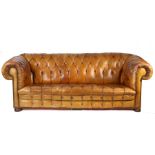 A leather upholstered chesterfield sofa, the button back and scroll arms above the button seat and
