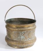A brass repouseé log basket With swing handle and floral decoration, 40cm diameter, 31cm high to
