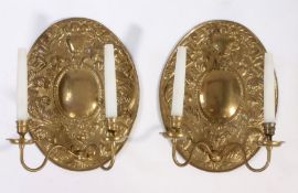 A pair of 17th century style brass repouseé wall sconces Fitted for electricity, each with oval back