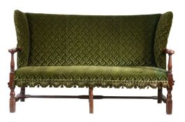 An 18th Century fruitwood and upholstered wingback sofa, upholstered in foliate green velvet, the