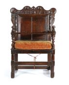 An unusual oak open armchair, Cumbria, dated 1718 The scroll arched top rail carved with