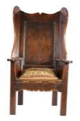 A George III joined oak 'lambing-type' wing armchair, circa 1760 Having a panelled back, ogee-