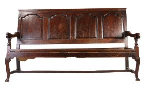 A George II oak settle, circa 1750 Having a rectangular back of for flattened ogee-arched fielded