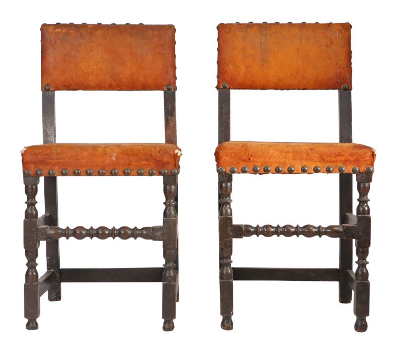 A pair of Charles II oak and hide upholstered chairs, circa 1670 Each with rectangular padded open