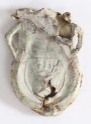 A medieval lead pilgrims Ampulla, with a flower motif to one side and a crest to the opposing