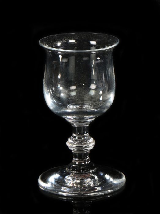 A George III glass, with a flared lip above the bowl and a ring stem on wide arched foot with pontil