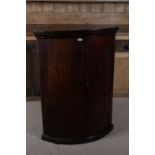 George III mahogany bow fronted hanging corner cupboard, with a pair doors opening to reveal three