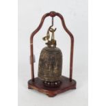 Chinese bronze bell and stand, the bell of archaistic form and dragon handle housed within the