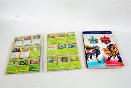 A folder of Pokémon cards together with The Official Galar Region Strategy Guide