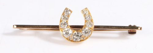 Yellow metal and diamond horse shoe bar brooch, the horse shoe set with nine graduated diamonds,