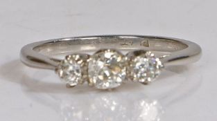 Platinum three diamond set ring, the central round cut diamond flanked by a further diamond to