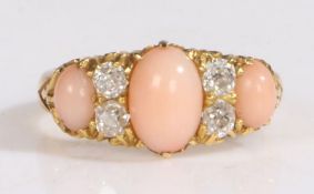 An 18 carat gold "angel skin" coral and diamond set ring, with three cabochon cut corals and four
