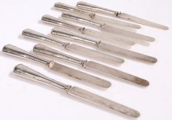 Nine French silver handled dessert knives, the steel blades stamped "ODIOT", the ribbon and bow