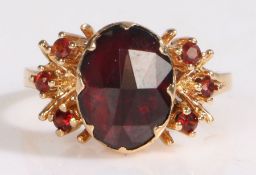 An 18 carat gold garnet set ring, with a central garnet and further garnets to the shoulders, ring