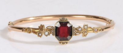 A yellow metal garnet and pearl set bracelet, with a central garnet flanked by pearl set leaves, 9.