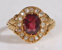 An 18 carat gold ruby and diamond ring, the central oval ruby with a diamond surround, ring size
