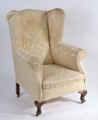 Edwardian wingback armchair, upholstered in a cream foliate material, raised on cabriole legs and