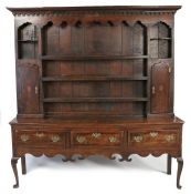 18th century oak dresser, having dental moulding above a scroll frieze, three shelves flanked by a