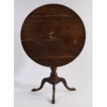 George III oak tripod table, the circular tilt-top raised on a turned stem, tripod legs and pad