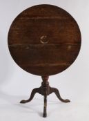 George III oak tripod table, the circular tilt-top raised on a turned stem, tripod legs and pad