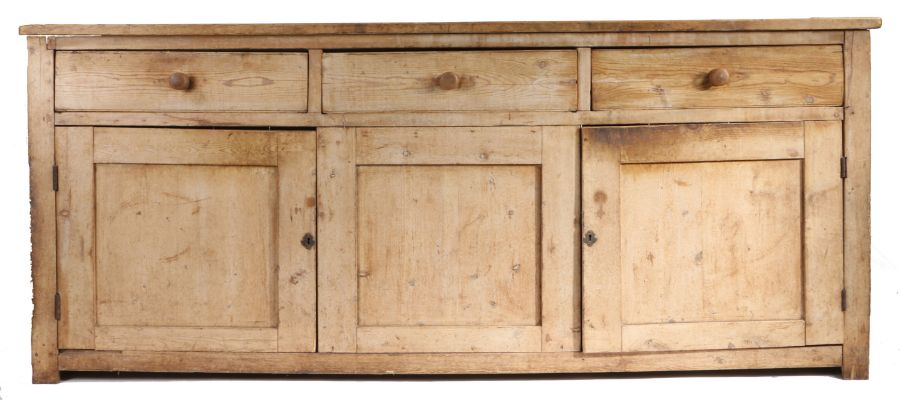 A 19th Century pine dresser base, the rectangular top above three short drawers and three cupboard