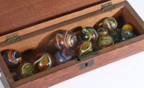 A collection of 19th century coloured twist glass marbles, largest 36mm diameter, in mahogany lidded