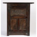 A part 17th Century oak cupboard, the rectangular top above a panelled door with carved lozenge