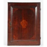 A George III oak and marquetry-inlaid mural cupboard, circa 1780 The single fielded panelled