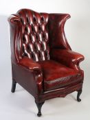 Queen Anne revival chesterfield wingback armchair, in red leather with button back, raised on
