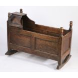 George III oak crib, the canopied top and turned finials above panelled ends and sides, raised on
