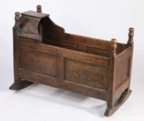 George III oak crib, the canopied top and turned finials above panelled ends and sides, raised on