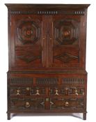 An oak cupboard, in the Charles II style, the concave cornice above a pair of panel doors with