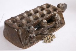 An African mancala board, carved with three figure to each side and head to one end, together with