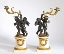 A pair of 19th Century French bronze and ormolu candlesticks, modelled as cherubs holding aloft