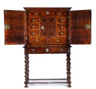 A fine William & Mary oyster veneered cabinet and stand, the swept pediment above two oyster
