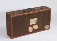 An oversized French suitcase, in the Louis Vuitton manner, with brass corner mounts and plaque to