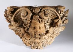 An 18th century French carved lime wood wall bracket, depicting a cherubs head with wings surrounded