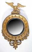 A Regency giltwood convex wall mirror, the circular mirror plate housed in an ebonised slip, the