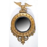 A Regency giltwood convex wall mirror, the circular mirror plate housed in an ebonised slip, the