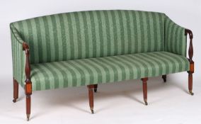 A Regency mahogany and upholstered three seater settee, with a green striped fabric raised on reeded