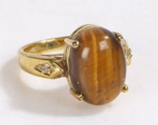 Yellow metal and tigers eye ring, the head set with a claw mounted oval tigers eye stone, ring