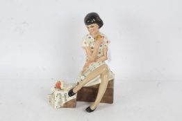 Lenci pottery figurine, (Italian), in the form of a seated girl holding and apple with a book beside